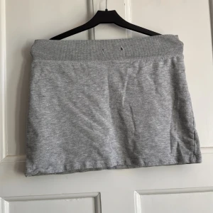 Grå kortkjol från BikBok - Enkel och snygg grå kortkjol från BikBok i mjukt bomullsmaterial. Kjolen har bred resår i midjan och är perfekt för en chill och avslappnad look. Passar dig som gillar basic och stilrena plagg.