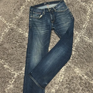 Tommy Jeans straight fit jeans blå - Snygga blå jeans från Tommy Jeans i modellen Original Straight Ryan. Klassisk femficksdesign, raka ben och mellanblå tvätt med lätt slitning. Perfekta för dig som gillar en tidlös och clean look. Materialet är robust denim i bomull.