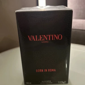 Valentino Uomo Born In Roma 100ml - Exklusiv herrparfym från Valentino, Born In Roma Uomo. Kommer i en elegant svart kartong med röd text och diskret mönster. Eau de Parfum, 100 ml. Perfekt för dig som vill ha en modern och lyxig doftupplevelse.
