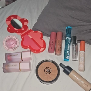 Stort sminkpaket - Paket med smink: rosa highlighter från SHEGLAM, två nude/rosa blush från SHEGLAM, duo-rouge i rött och korall, bronzer från revolutionen Pro, foundation från Revolution Pro, concealer från W7, läppglans och läppolja från Makeup Mekka och W7, samt volymgivande läppglans från Catrice. Kolla gärna in min profil för mer.