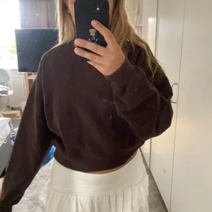 Mörkbrun croppad sweatshirt - Mysig mörkbrun croppad sweatshirt med rund hals och långa ärmar. Tröjan har en loose passform och är perfekt för en chill och avslappnad stil. Tillverkad i mjukt bomullsmaterial som känns skönt mot huden.