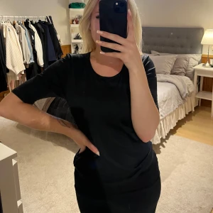 Svart basic t-shirt från Fransa - En svart, enkel t-shirt från Fransa med rund halsringning och korta ärmar. Modellen är klassisk och passar perfekt till jeans eller kjol. T-shirten har en normal passform som sitter snyggt på kroppen. Materialet är ungefär som träningsmaterial och är därför väldigt stretchigt och bekvämt. 