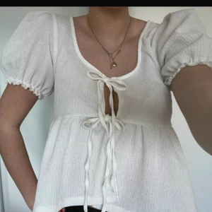 Vit blus med puffärm från Gina Tricot - Supersöt vit blus från Gina Tricot med puffiga korta ärmar och två knytningar framtill. 