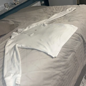 Vit långärmad tröja från Polo Ralph Lauren - Säljer en stilren vit långärmad tröja från Polo Ralph Lauren med dragkedja vid halsen. Tröjan har en liten broderad logga på bröstet och är perfekt för en avslappnad look. Passar bra till både jeans och chinos. Pris kan diskuteras.