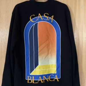 Svart långärmad tröja från Casablanca - Säljer nu en svart exklusive tröja från Casablanca i 100% ekologisk bomull. Tröjan har en färgglad grafisk design på ryggen och en liten logotyp på bröstet. Perfekt för en stilren och unik look som fångar ögonen. Fint skick Nypris 3599kr