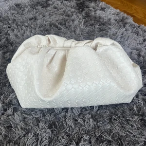 Vit pouch väska med axelband - Snygg och rymlig creame vit pouch väska med optionell axelband. flätat mönster och med innerficka. jättefin och perfekt för sommaren🌸🌸 fråga gärna om du undrar något. 