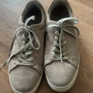 Grå sneakers från Iguassu - Snygga grå sneakers från Iguassu med snörning. Skorna har en stilren design med en ovandel i mocka och en vit sula. Perfekta för en avslappnad stil.