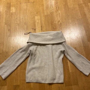 Beige stickad tröja från H&M - Säljer en stilren beige stickad tröja från H&M. Tröjan har en bred krage som kan bäras offshoulder och långa ärmar. Perfekt för kyligare dagar. ✨💕