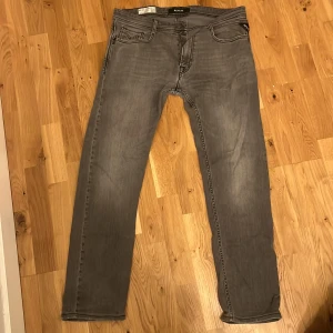 Grå jeans från Replay - Snygga grå jeans från Replay med en klassisk femficksdesign. De har en rak passform och är tillverkade i ett slitstarkt denimtyg. Perfekta för en stilren look.