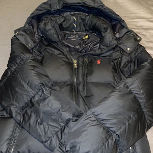 Svart dunjacka från Polo Ralph Lauren -  svart dunjacka från Polo Ralph Lauren med huva och dragkedja. Köptes på NK för 5 000kr. Tyvärr har jag inte kvar kvittot på jackan :(.  Men QR kod finns förstås på jackan. Säljer den för 2500 men kan absolut gå ner i pris vid seriösa köpare och snabb affär 