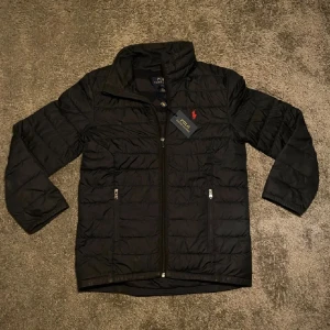 Svart Ralph Lauren Terra - Hej! Säljer nu min Ralph Lauren jacka då den var för liten. Om mått behövs så kan jag fixa det! Perfekt nu för våren då den är tunn, men också rätt så varm. Den är i väldigt bra skick. Du får med Jackan och Tag. Jag har valt att sätta priset till 850kr. Jag kan byta mot andra Ralph Lauren jackor! Har du några frågor ska du inte tveka att höra av dig!