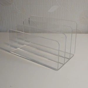 Transparent bokhållare  - Säljer en stilren och modern transparent bokhållare/brevhållarei hård plast. Perfekt för att organisera böcker eller dokument på skrivbordet. Den har tre fack och en minimalistisk design som passar in i alla miljöer.
