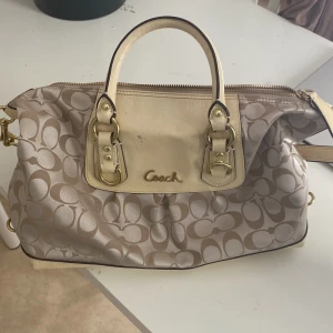 Coach handväska  - Säljer en snygg y2k beige handväska från Coach. Väskan har både handtag och en justerbar axelrem i ljusare beige. Den är äkta, har lite fläckar men annars är den helt ny! Priset kan diskuteras 