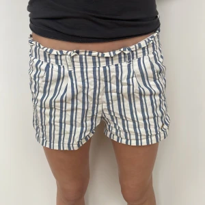 Randiga shorts från Hampton Republic - Säljer ett par snygga randiga shorts från Hampton Republic. De är vit- och blårandiga med en bekväm passform och elastisk midja. Storleken säger 130 men jag är 13 och får på mig dom!