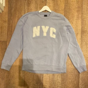 Ljusblå Sweatshirt från Only & Sons - Säljer en ljusblå sweatshirt från Only & Sons med texten 'NYC' i vitt på framsidan. Tröjan har långa ärmar och en rund halsringning. Perfekt för en avslappnad stil. Storlek Small. Snabb Leverans!