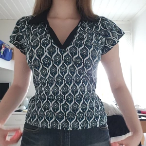 Mönstrad topp - Snygg mönstrad topp med svart krage och v-ringning💚 Den har korta klockformade ärmar och ett knytband i ryggen som man kan dra åt vid midjan. Perfekt för till exempel fest💞 Skriv gärna vid frågor eller intresse🫶