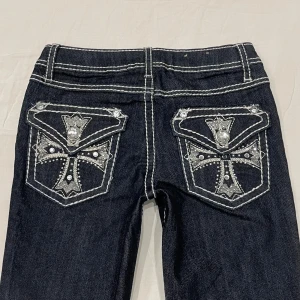 Lågmidjade bootcut jeans med broderade bakfickor - Läs bio innan köp!!! Midja 32 cm rakt över plus stretch, gren 18 och innerben 70 cm💕jag är 169 och xs-s och de är försmå och för korta så tar inga bilder med dem på