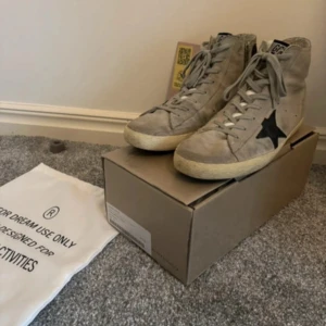 Golden goose - Snygga grå sneakers från golden goose med en svart stjärna på sidan och en blå rand baktill. Skorna har snörning och en bekväm sula. Perfekta för en avslappnad stil. OBS!! Endast skor ingår. Inte box