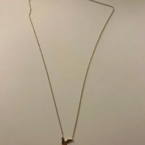 Guldigt halsband med fågelhänge - Snyggt och minimalistiskt halsband i guld med ett litet fågelhänge. Kedjan är tunn och elegant, perfekt för dig som gillar stilrena smycken med en personlig touch. Passar till alla tillfällen och är lätt att matcha med andra smycken.
