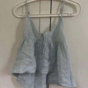 Ljusblå babydoll topp - Supersöt ljusblå linnetopp med volanger och tunna axelband. I storlek M men passar mig som har S.