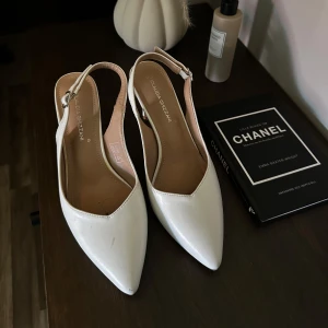 Vita klackar med spetsig tå från Claudia Ghizzani - Superfina vita klackskor från Claudia Ghizzani. Skorna har ett justerbart spänne baktill vilket gör att de passar fler. Storlek 40 men passar mer som 39.  