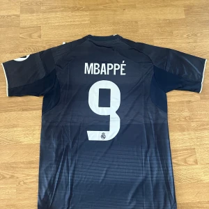 Real Madrid Mbappé matchtröja 25/26 - Real Madrids bortaställ för säsongen 25/26 med 9 Mbappe på ryggen. Helt ny!