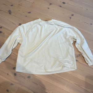 Vit långärmad sweatshirt - Enkel och stilren vit långärmad sweatshirt i mjukt material. Tröjan har rund halsringning och ribbade muddar vid ärmslut och hals. Perfekt för en avslappnad och clean look.