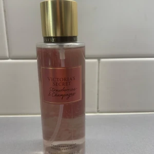 Ny! Victoria's Secret Strawberries & Champagne - Fräsch body mist från Victoria's Secret med doft av jordgubbar och champagne. Flaskan är genomskinlig med rosa vätska och har en guldig kork. Perfekt för dig som gillar söta och bubbliga dofter.