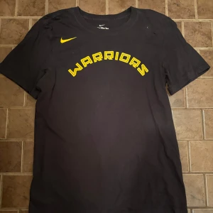 NBA Warriors Nike T-shirt - Säljer denna t-shirten ifrån Nike! Knappt använd och inte skavanker. Sitter riktigt fint👏Väljer du att betala direkt via Swish kan jag gå ner lite i pris eftersom vi då slipper all väntetid som tillkommer via betalning genom Plick!🏆 Skicka ett PM vid frågor eller funderingar.