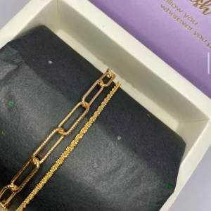 Tvådelat guldarmband med kedjor - Snyggt tvådelat armband i guldton, ett med större rektangulära länkar och ett med tunn, glittrig kedja. Perfekt för dig som gillar att mixa olika stilar och vill ha något som sticker ut på handleden. Ej använd utan kommer från min small bussines. 