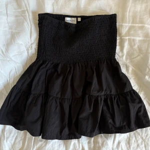 Svart volangkjol från Carin Wester - Supersöt svart kortkjol från Carin Wester med smockad midja och flera volanger. Aldrig använd, köpt i fel storlek 