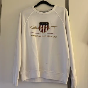 Vit sweatshirt från GANT med tryck - Vit sweatshirt från GANT med klassiskt tryck och broderad logga framtill. Tröjan har rund hals, långa ärmar och ribbade muddar. Perfekt för en clean och sportig look. Materialet är mjuk bomull som känns skönt mot huden. Säljer i storlek 170💞
