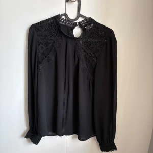 Svart blus med mönster från Cubus - Säljer en svart blus med mönster på axlarna från Cubus. Knapp längst upp vid nacken. Används en gång. Mycket bra skick. Pris kan diskuteras. 
