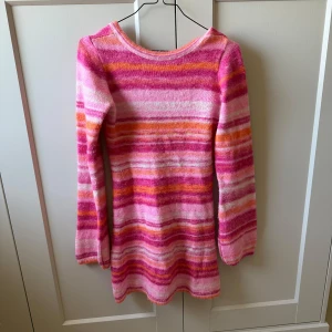 Randig rosa stickad tröja Nelly XS - Superfin stickad klänning från Nelly i storlek XS. Tröjan har ett färgglatt randigt mönster i rosa, orange och vitt, med lång ärm och rund halsringning. Perfekt för dig som gillar färg och mjuka plagg!