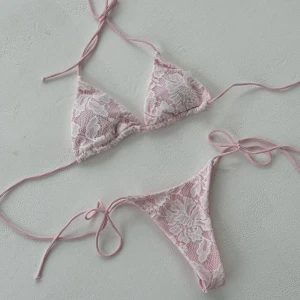 Bikini från designbysi - Säljer denna bikini då den var för liten för mig 😊Supersöt bikini i ljusrosa med vita spetsdetaljer och blommigt mönster. Triangeltopp och trosa med tunna knytband i sidorna för perfekt passform.