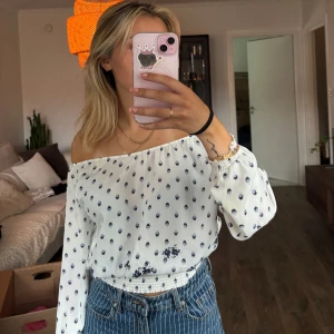 Vit blus med blått mönster från Kappahl - Vit offshoulder topp med blått mönster. Jag har även valt att ibland bära den som en vanlig blus med ”axlarna uppe”. Är i barnstorlek 146/152.