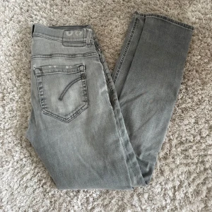 Grå dondup jeans - Säljer ett par ljusgrå dondup jeans i modellen george, jeansen har två snygga slitningar på högra benet. Vid frågor eller funderingar tveka inte på att höra av dig!