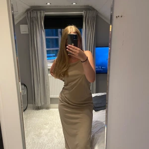 Beige långklänning från H&M - Säljer en stilren beige långklänning från H&M i storlek S. Klänningen har smala axelband och en rak, figurnära passform. Tillverkad i mjuk polyester som ger ett snyggt fall. 