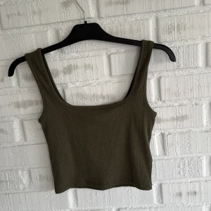 Olivgrön ribbad croppad linnetopp - Grönt linne från lager 157, storlek XS men passar även mig som är en S. Prislappen kvar så aldrig använd😊
