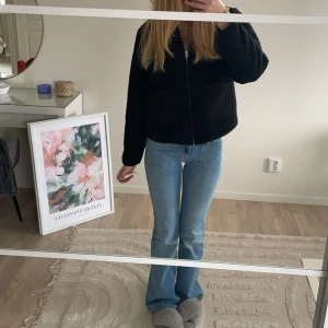Ljusblå bootcut jeans lågmidjade - Säljer ett par ljusblå jeans med bootcut-modell och klassisk femficksdesign. Jeansen har normal passform och är tillverkade i mjukt denimtyg som sitter snyggt över höfterna och låren. Perfekta för dig som gillar en tidlös och avslappnad look.