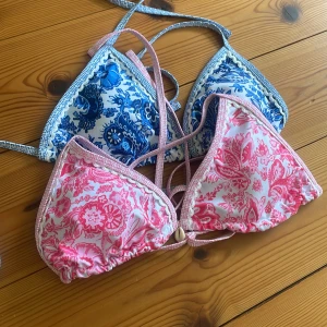 Blommig bikini i blått och rosa - Superfin bikini med blommigt mönster i blått och rosa på vit botten. Triangeltopp och klassiska bikinitrosor med snörning i sidorna.  Köpta på shein, har använt den rosa överdelen en gång annars inget, då de inte passar 