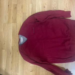 Vinröd tröja från Massimo Dutti 3XL - Vinröd långärmad tröja från Massimo Dutti i storlek 3XL. Tröjan har v-ringad hals med ribbade kanter och broderad logga på bröstet. Tillverkad i mjuk bomull, perfekt för lager-på-lager och snygg till jeans.