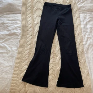 Svarta bootcut byxor från Name It - Svarta byxor från Name It med bootcut-modell och stretchigt material. Enkel design med hög midja och utsvängda ben.