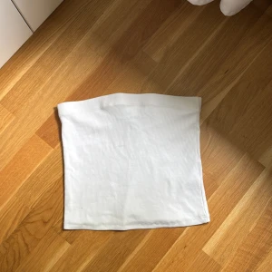 Vit bandeau tubtopp - Enkel och stilren vit bandeau tubtopp i ribbad bomull. Toppens raka form ger en clean look och den är ärmlös för maximal frihet. Den har ett elastisk band runt som gör att toppen inte åker ner. Toppen är i storlek L men är liten i storlek så skulle säga att den sitter som en M.💕💕