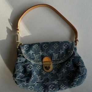 Louis Vuitton denim handväska - Säljer en ikonisk handväska från Louis Vuitton i blått denimtyg med klassiskt monogrammönster. Väskan har guldfärgat spänne, läderdetaljer och ett gult innerfoder i mocka. Perfekt storlek för det viktigaste och en snygg accessoar till din outfit. 💖