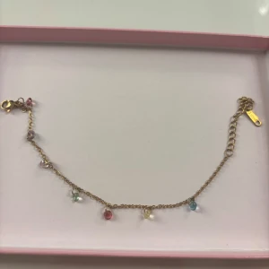 Guldfärgat armband med färgglada pärlor - Säljer ett fint armband med färgade stenar och guldfärgad kedja.💞Armbandet är endast använt ett fåtal gånger.