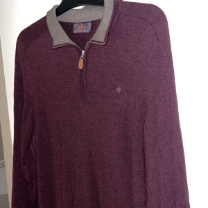 Morris tröja  - Vinröd stickad tröja från Morris i 100% merinoull. Tröjan har halv dragkedja med läderdetalj, kontrastfärgad krage i grått och broderad logga på bröstet. Perfekt för dig som gillar klassisk och stilren look. Tröjan är storlek xxl passar L