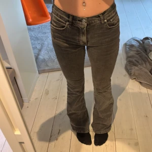 Grå bootcut jeans - Säljer ett par gråa bootcut jeans med klassisk femficksdesign och hög midja. Jeansen har en snygg tvätt och raka ben som slutar i en lätt utsvängning. Byxorna har tyvärr en nagellims fläck på insidan av låret men ingenting som syns vid användning