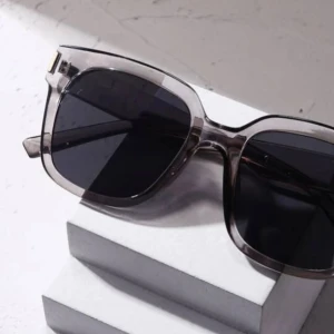 Grå transparenta solglasögon med svarta glas - Stilrena solglasögon med transparent grå båge och svarta fyrkantiga glas. Snygg detalj i guld vid gångjärnen. Perfekta för dig som vill ha en modern och trendig look.