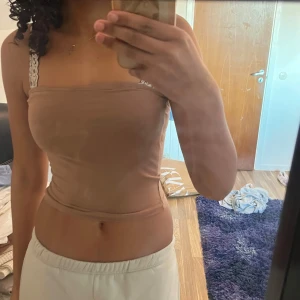 Beige tubtopp - Säljer en enkel och stilren beige tubtopp. Toppen är ärmlös och har en tight passform, perfekt att matcha med olika outfits. Materialet känns mjukt och stretchigt.